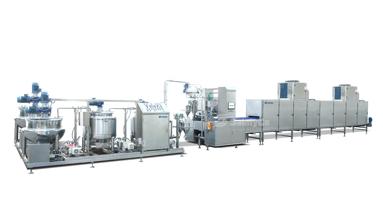 A sophisticated industrial food processing line featuring multiple interconnected stainless steel machines, including mixing tanks, piping systems, a gummy depositor, automated control panels, and a conveyor belt system. The setup is designed for large-scale production.