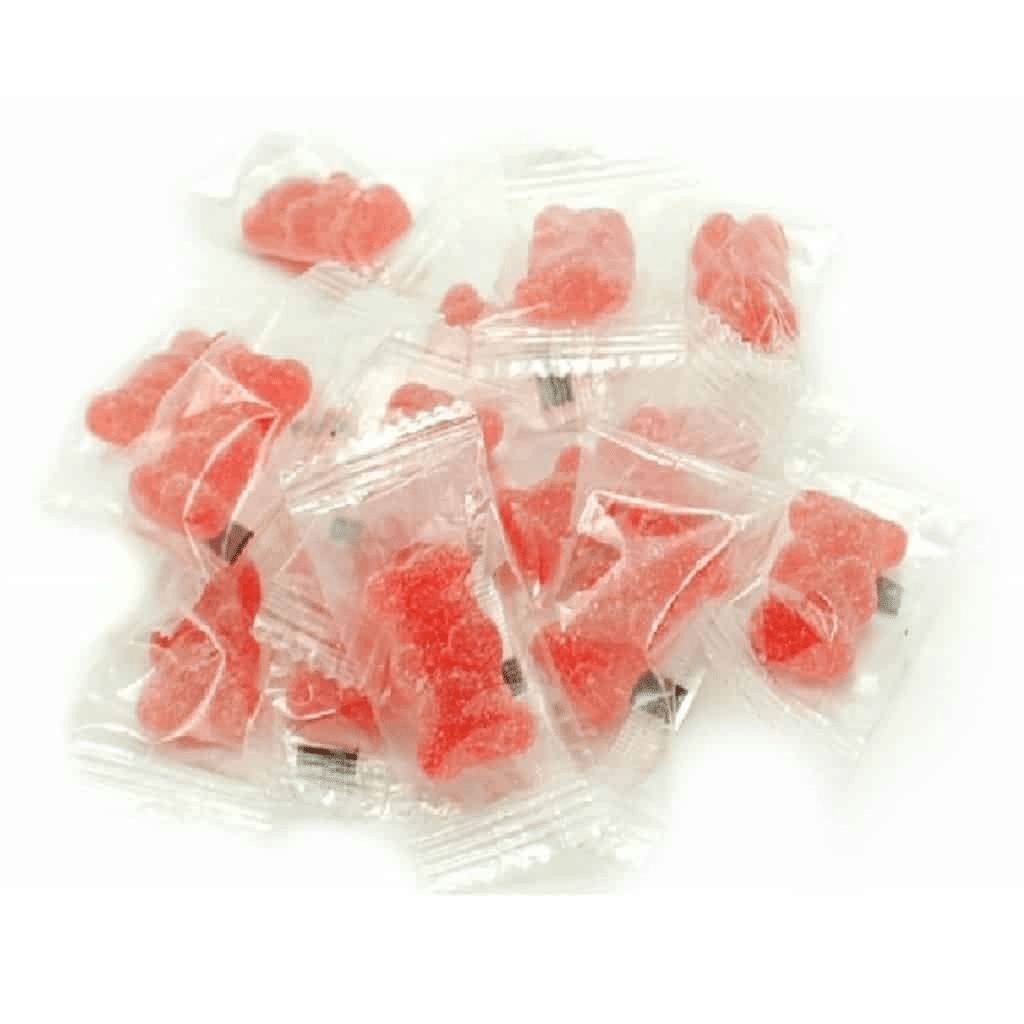 A pile of individually wrapped red gummy bears in clear plastic packaging, scattered on a white surface. Each package contains a single gummy bear, clearly visible through the transparent wrapping, a testament to the precision of the gummy making machine.