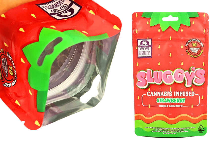 A vibrant, strawberry-themed packaging labeled "Sluggy's Cannabis Infused Strawberry Indica Gummies." The front has a viewing window showing the gummies inside, crafted using a state-of-the-art gummy making machine. The package highlights key information like THC content and a "No BRC THC" badge.