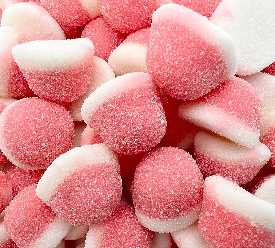 A close-up image of numerous pink and white sugar-coated gummy candies piled together. The candies, likely crafted using advanced gummy manufacturing equipment from Gummygenix, have a dome shape with a pink top and a white bottom, all with a granular, sugary texture visible on the surface.