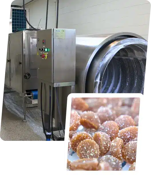 A large industrial machine, likely one of SaintyCo's GummyGenix gummy making machines, features a control panel with buttons and switches. Inset is an image of sugar-coated brown candies. The backdrop shows a tiled wall and a clean, industrial setting.