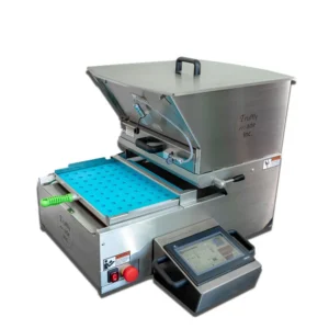 A stainless steel candy depositor machine with an open top and blue mold tray. It features a handle, touchscreen control panel, and emergency stop button. The design is industrial and functional, suitable for confectionery production.