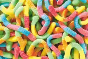 A close-up of colorful gummy worms covered in sugar. The candies are twisted and intertwined, with vibrant shades of yellow, red, green, blue, and orange.